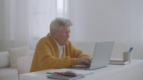 Senior-mature-older-woman-typing-a-message-on-the-keyboard-online-webinar-on-laptop-computer-remote-working-or-social-distance-learning-from-home.-60s-80s-businesswoman